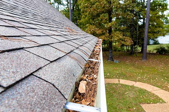 gutter maintenance worker removing leaves and dirt